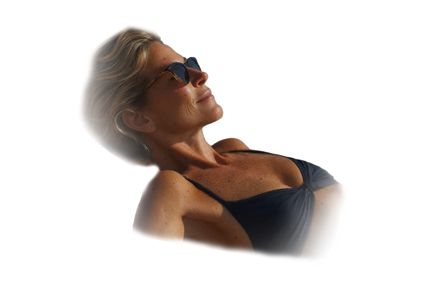 Mujer tomando el sol con gafas oscuras, con lunares visibles en hombros y escote